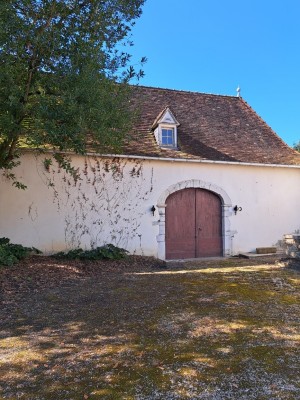 Facade blanche de la grange avec une porte ancienne à double batant et toit en tuiles plates